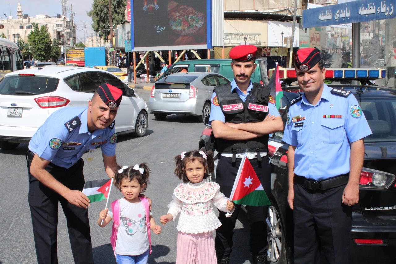 رجال الأمن يوزعون أعلام الوطن ويرفعونها مع أهلهم وعزوتهم